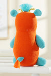 A stuffed toy with an orange body, blue limbs and ears, a blue tail, and a tuft of blue hair sits upright on a white surface.