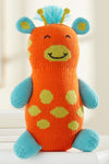 A knitted stuffed toy giraffe with an orange body, blue limbs and ears, yellow spots, a smiling face, and blue yarn hair on top.