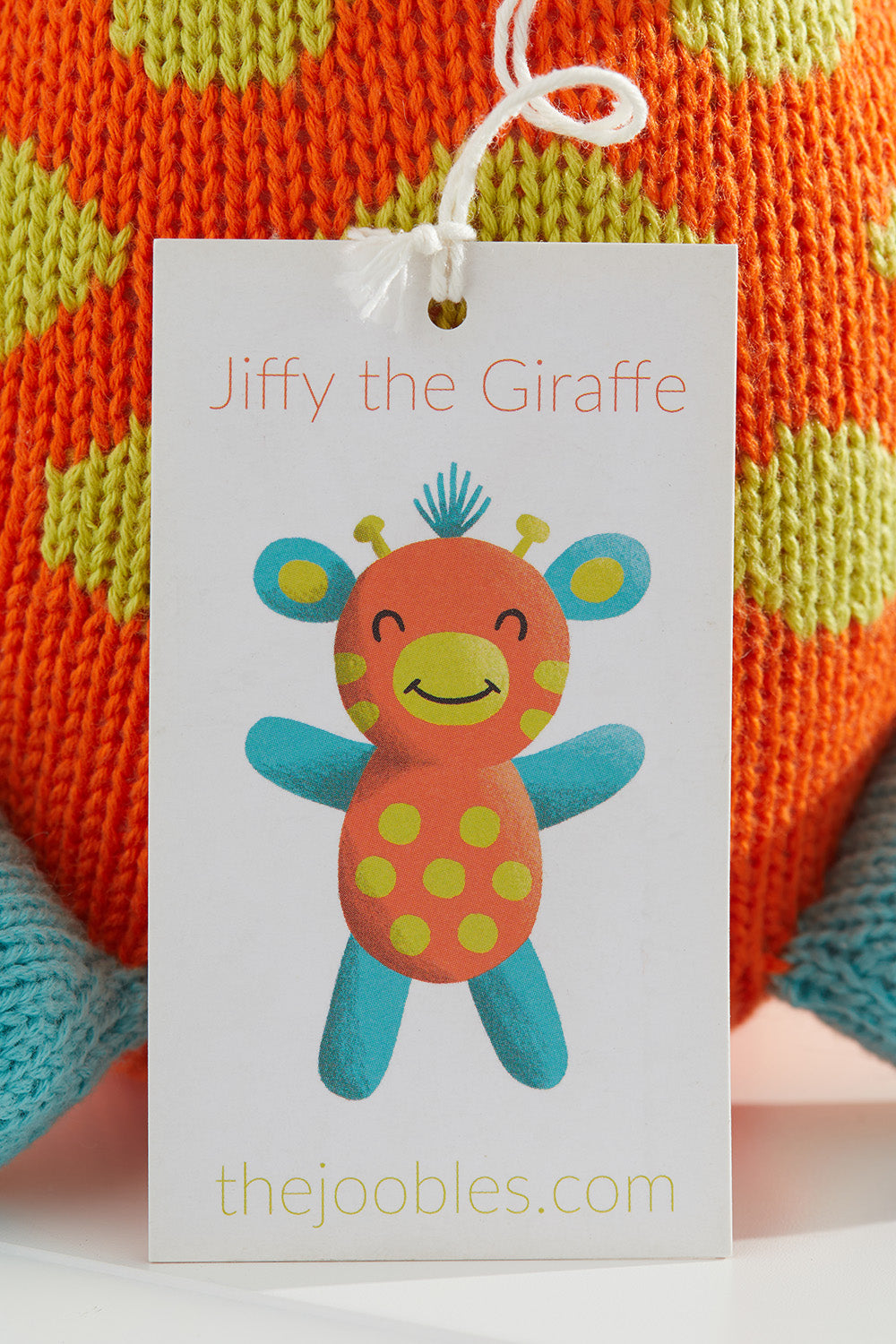 A tag displays an illustration of Jiffy the Giraffe, a colorful knitted toy, with the website thejoobles.com printed below.