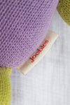 Close-up of a fabric tag labeled joobles attached to a knitted item in purple and green colors.